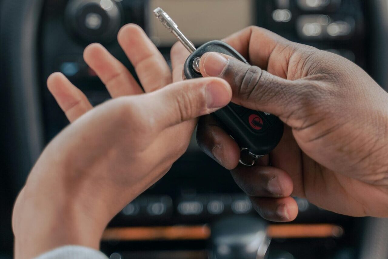 Two people exchanging car keys inside a luxury car, emphasizing guidance and learning.